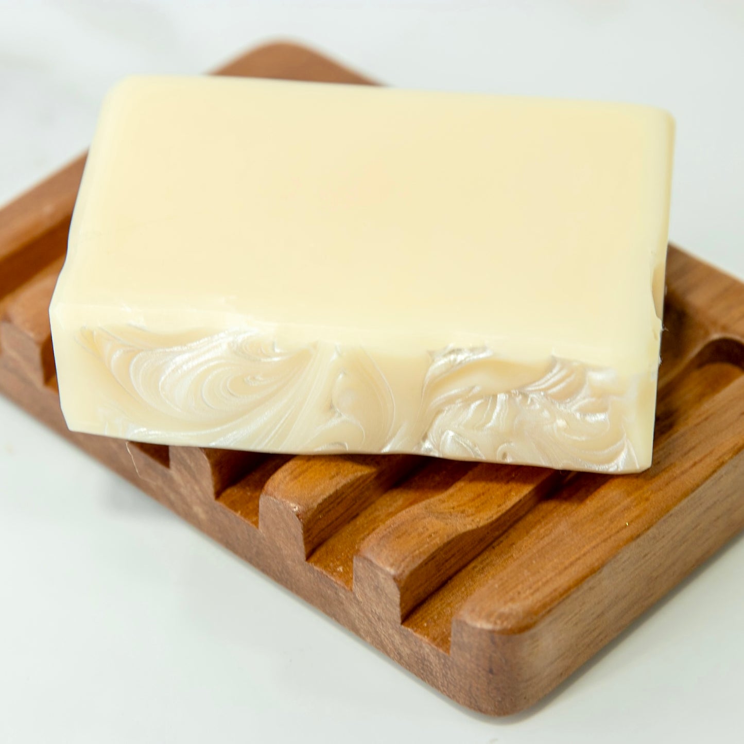Bar of soap on a wooden soap dish against a white background